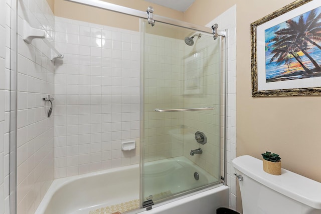 bathroom with toilet and shower / bath combination with glass door