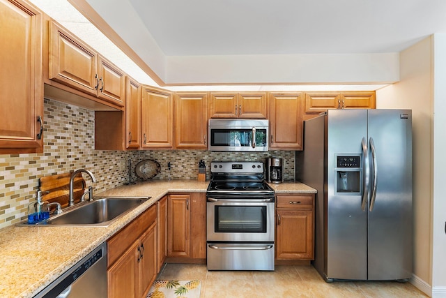 kitchen featuring decorative backsplash, stainless steel appliances, sink, and light stone counters