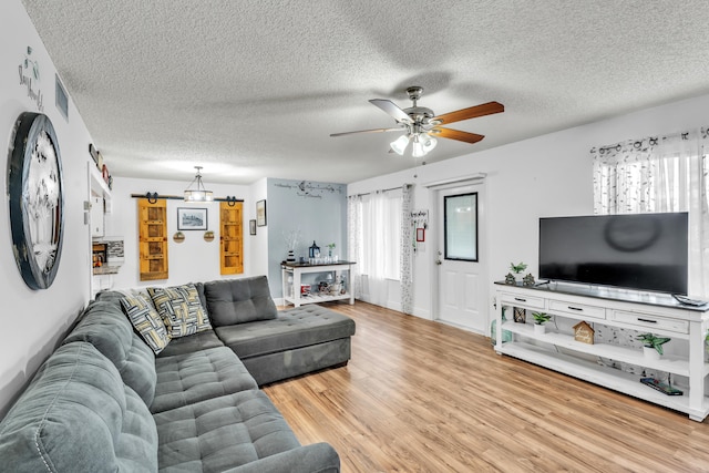 living room featuring hardwood / wood-style floors, ceiling fan, and a textured ceiling