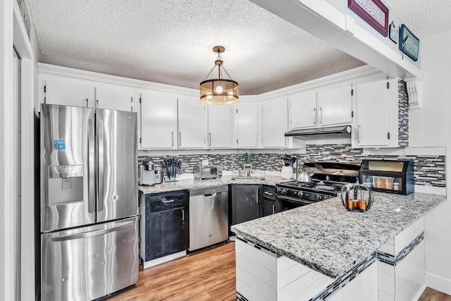 kitchen featuring stainless steel appliances, hanging light fixtures, white cabinetry, and light hardwood / wood-style flooring