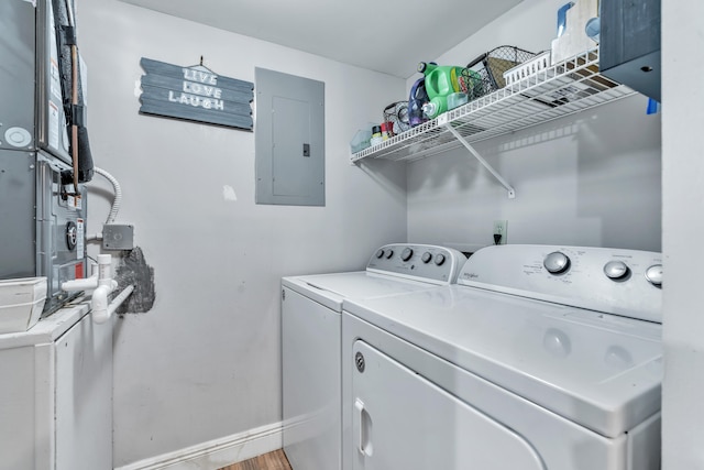 washroom featuring electric panel, washing machine and dryer, and wood-type flooring