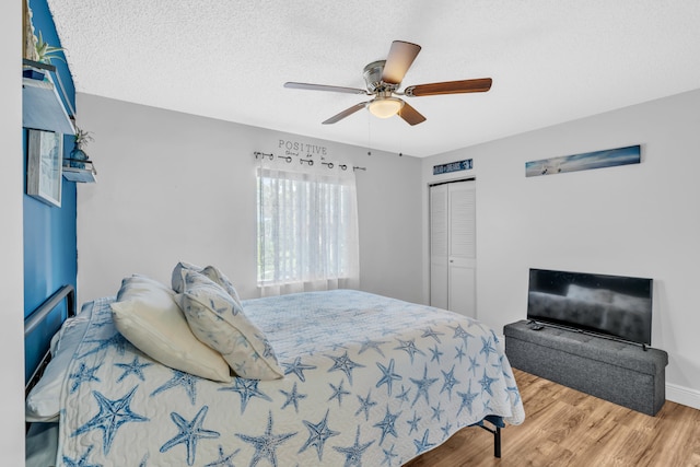 bedroom featuring ceiling fan, wood-type flooring, a textured ceiling, and a closet