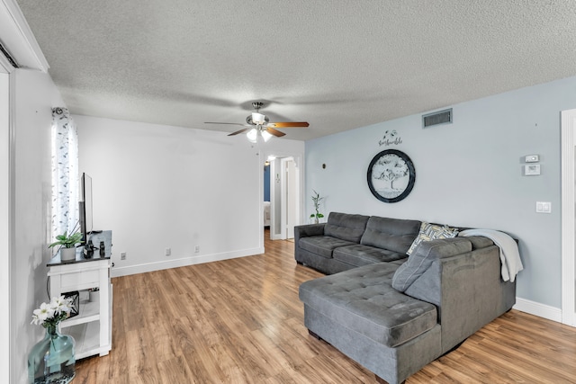 living room featuring light hardwood / wood-style floors, ceiling fan, and a textured ceiling