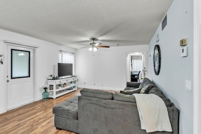 living room featuring a textured ceiling, wood-type flooring, and ceiling fan