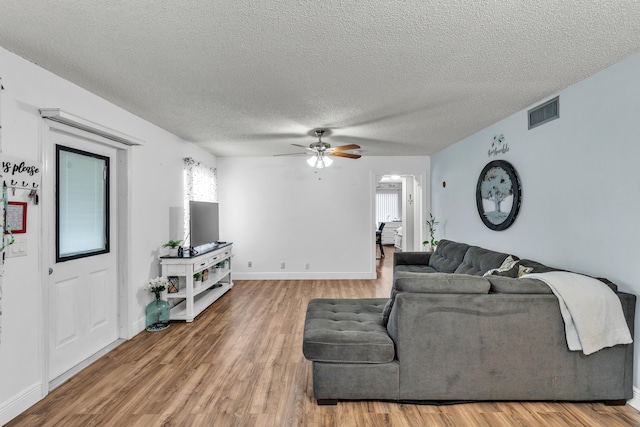 living room featuring ceiling fan, wood-type flooring, and a textured ceiling