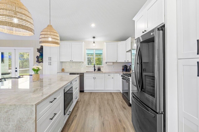 kitchen with french doors, light hardwood / wood-style flooring, decorative light fixtures, white cabinetry, and appliances with stainless steel finishes