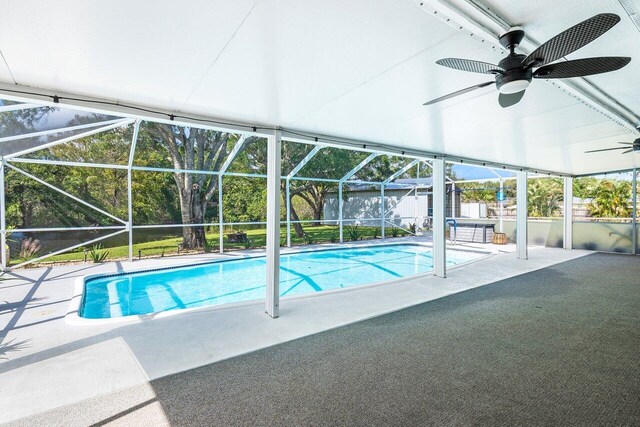 view of pool with a patio, glass enclosure, and ceiling fan