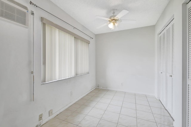 unfurnished bedroom featuring a textured ceiling, light tile patterned flooring, ceiling fan, and a closet