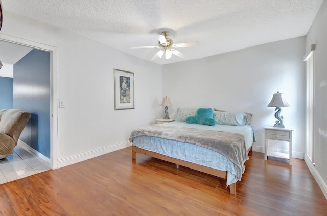 bedroom with a textured ceiling, hardwood / wood-style flooring, and ceiling fan