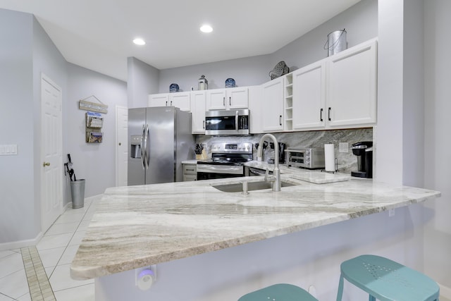 kitchen with kitchen peninsula, stainless steel appliances, white cabinets, and light tile patterned flooring