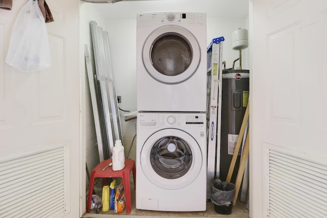 clothes washing area featuring electric water heater and stacked washer and clothes dryer