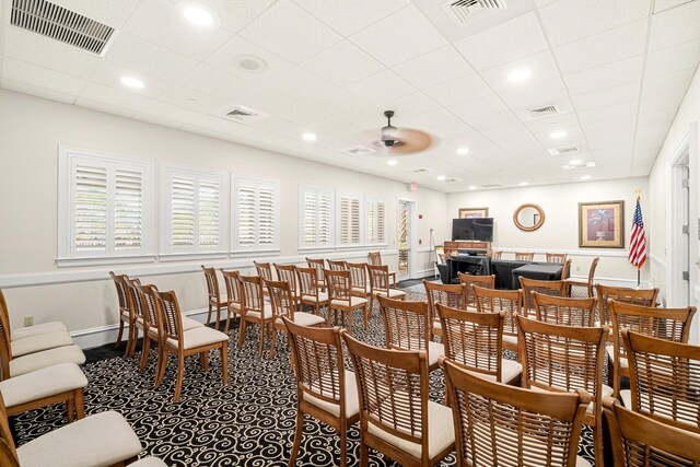 dining area with carpet flooring, a drop ceiling, and ceiling fan