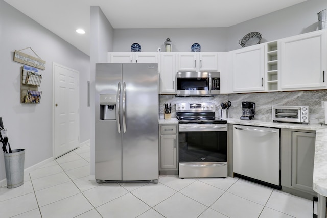 kitchen featuring white cabinets, decorative backsplash, stainless steel appliances, and light tile patterned flooring