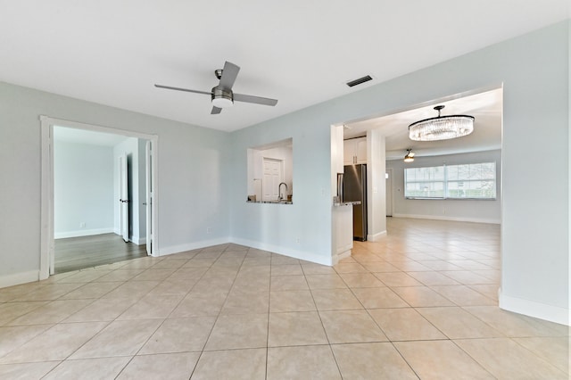 tiled spare room with sink and ceiling fan with notable chandelier