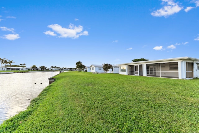 view of yard with a sunroom and a water view