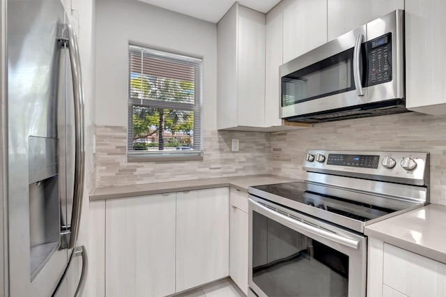 kitchen featuring stainless steel appliances, white cabinets, and tasteful backsplash