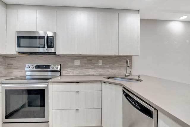 kitchen with decorative backsplash, white cabinetry, appliances with stainless steel finishes, and sink