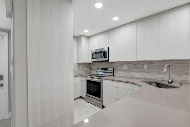 kitchen with white cabinets, sink, decorative backsplash, and appliances with stainless steel finishes