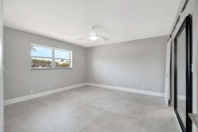 unfurnished bedroom with a barn door and ceiling fan