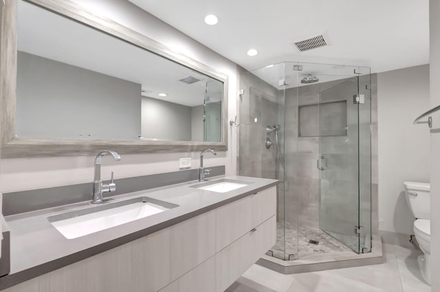 bathroom with a shower with shower door, vanity, toilet, and tile patterned flooring