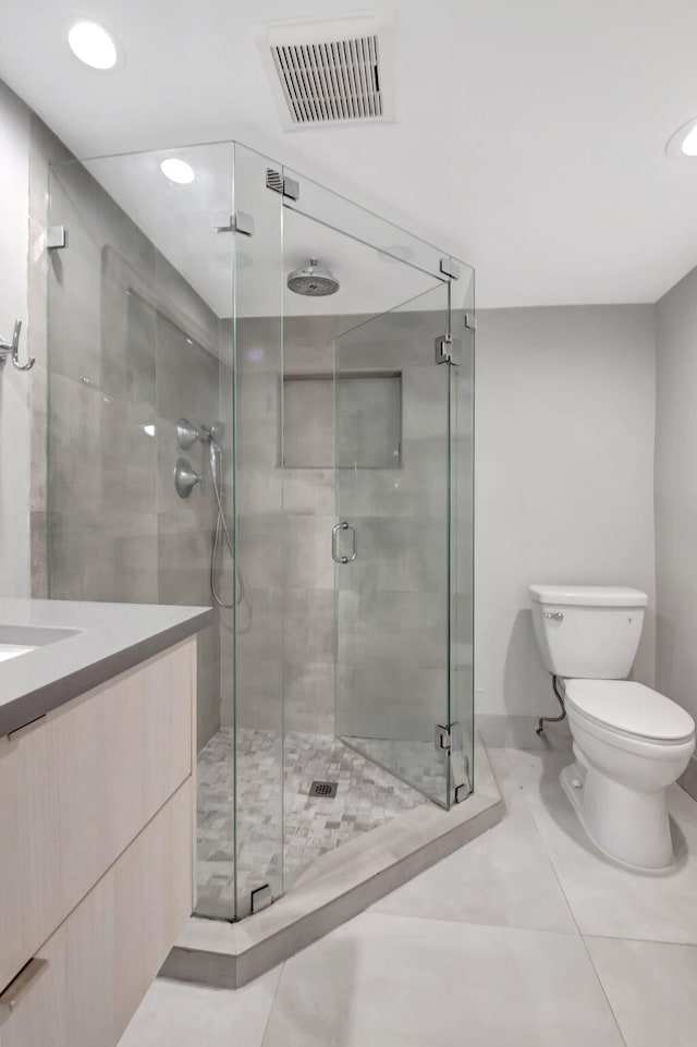 bathroom featuring vanity, a shower with shower door, tile patterned floors, and toilet