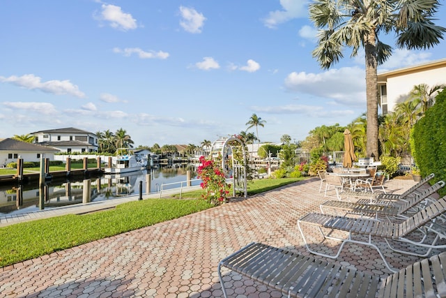 view of community featuring a dock, a water view, and a patio area