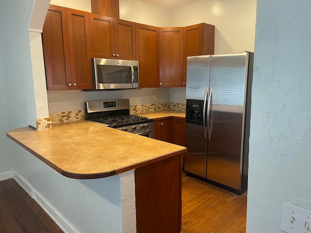 kitchen featuring stainless steel appliances, dark hardwood / wood-style flooring, and kitchen peninsula