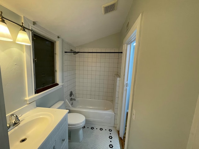 full bathroom featuring vaulted ceiling, toilet, vanity, tiled shower / bath combo, and tile patterned flooring