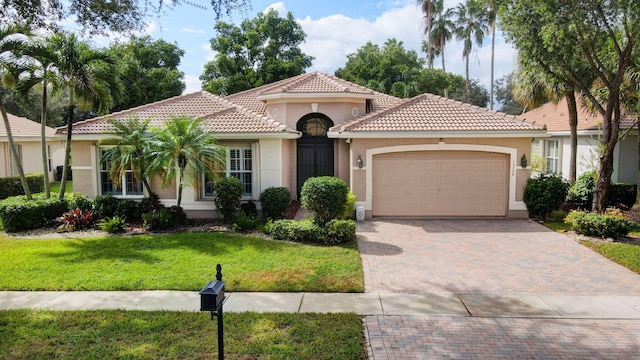 mediterranean / spanish home featuring a garage and a front yard