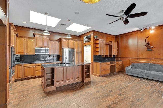 kitchen featuring decorative backsplash, a kitchen island, stainless steel appliances, a skylight, and decorative light fixtures