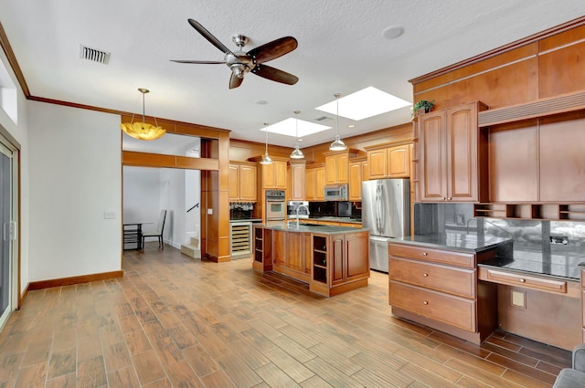 kitchen with light hardwood / wood-style flooring, stainless steel appliances, a center island, decorative light fixtures, and a skylight