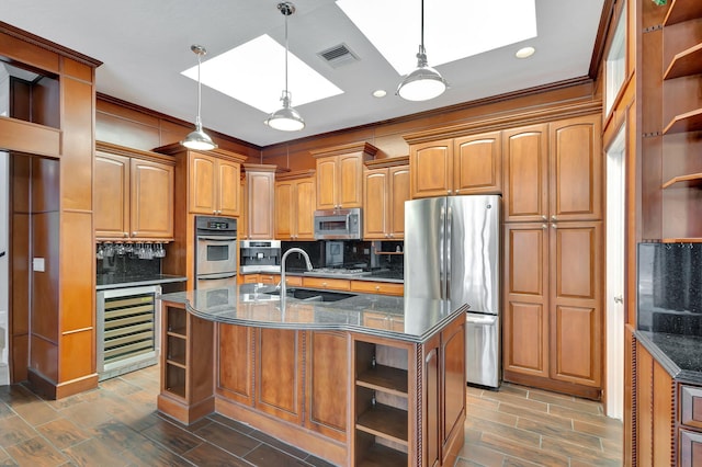 kitchen featuring wine cooler, an island with sink, sink, a skylight, and stainless steel appliances