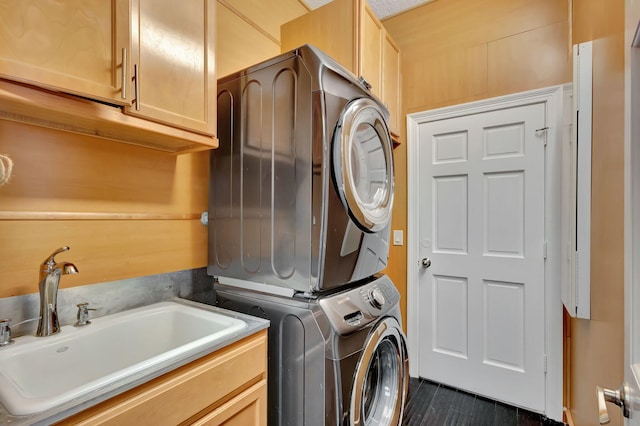 washroom featuring sink, stacked washer and clothes dryer, and cabinets