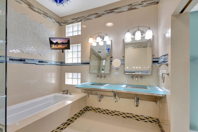 bathroom with vanity, tile patterned floors, tiled tub, and a healthy amount of sunlight