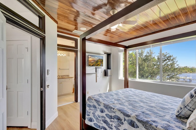 bedroom with light wood-type flooring, ceiling fan, wooden ceiling, beamed ceiling, and connected bathroom