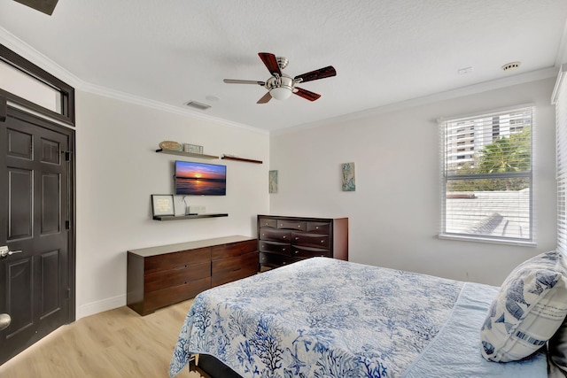 bedroom with crown molding, light wood-type flooring, and ceiling fan