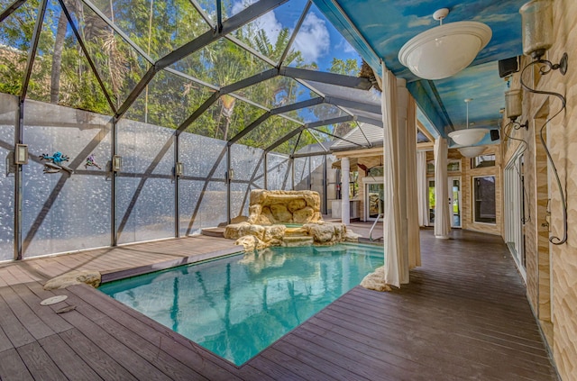 view of swimming pool featuring ceiling fan, a deck, and glass enclosure