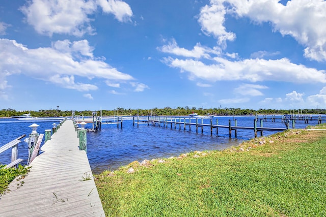 view of dock with a lawn and a water view