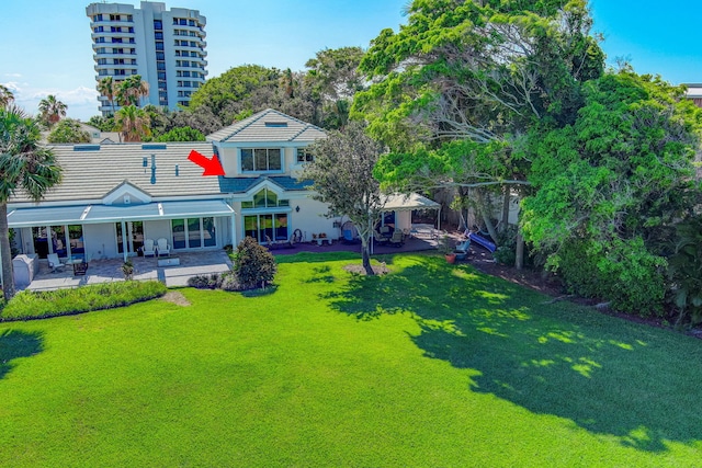 rear view of property featuring a patio and a lawn