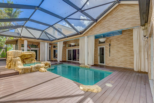 view of pool featuring a deck, glass enclosure, and ceiling fan