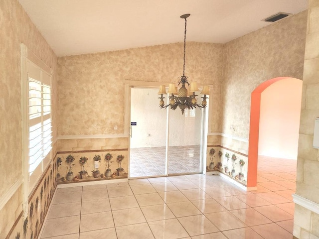 tiled spare room with an inviting chandelier