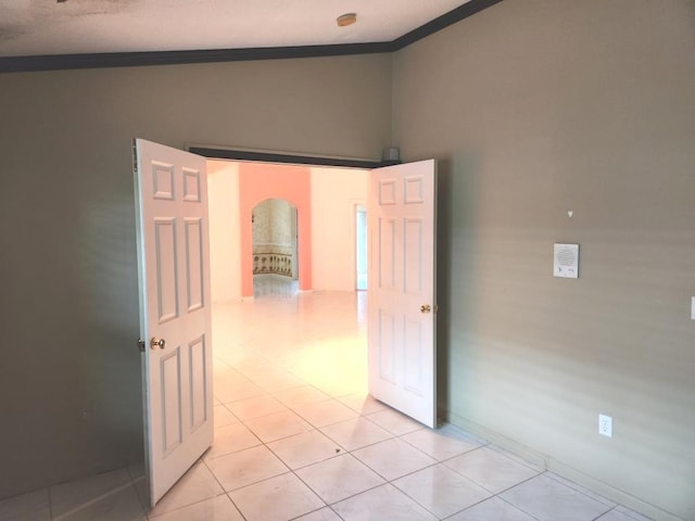 interior space with crown molding, vaulted ceiling, and light tile patterned floors