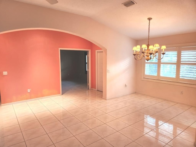 tiled empty room featuring a notable chandelier and vaulted ceiling