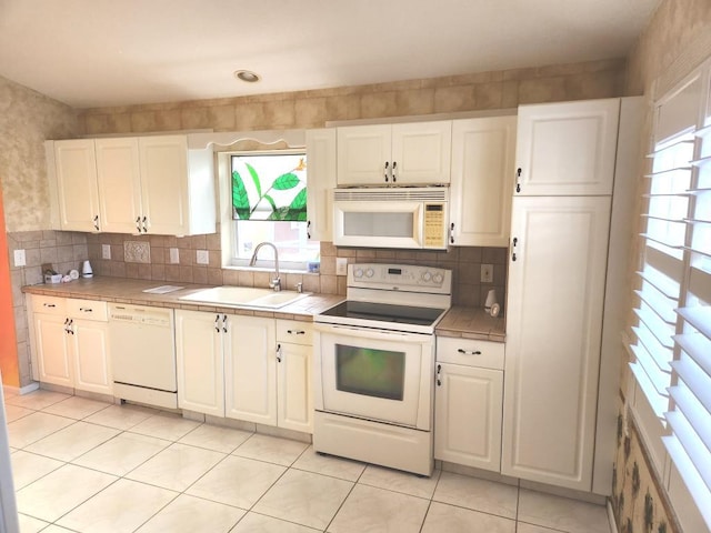 kitchen featuring white cabinetry, a healthy amount of sunlight, sink, and white appliances