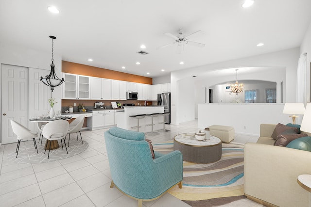 tiled living room with ceiling fan with notable chandelier