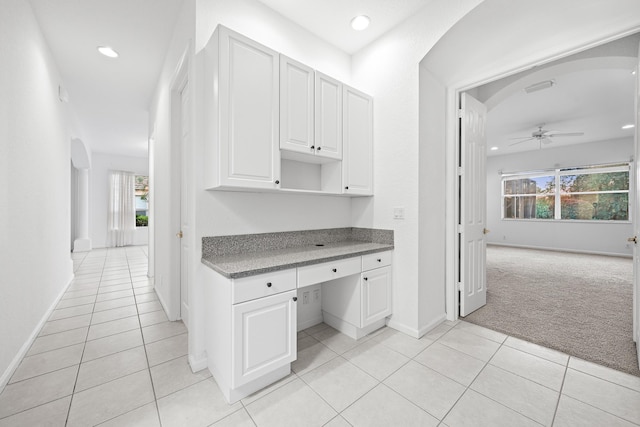 kitchen with built in desk, white cabinets, light carpet, and a healthy amount of sunlight