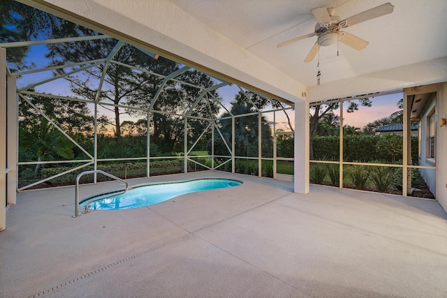 pool at dusk with a lanai, a patio area, and ceiling fan