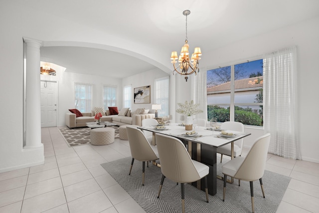 dining area featuring an inviting chandelier, a healthy amount of sunlight, ornate columns, and light tile patterned floors