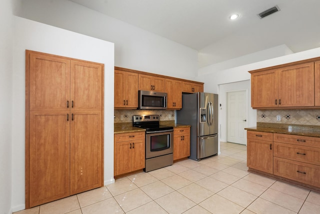 kitchen with dark stone counters, tasteful backsplash, appliances with stainless steel finishes, and light tile patterned floors