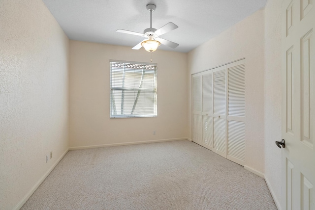 unfurnished bedroom with ceiling fan, light carpet, and a closet